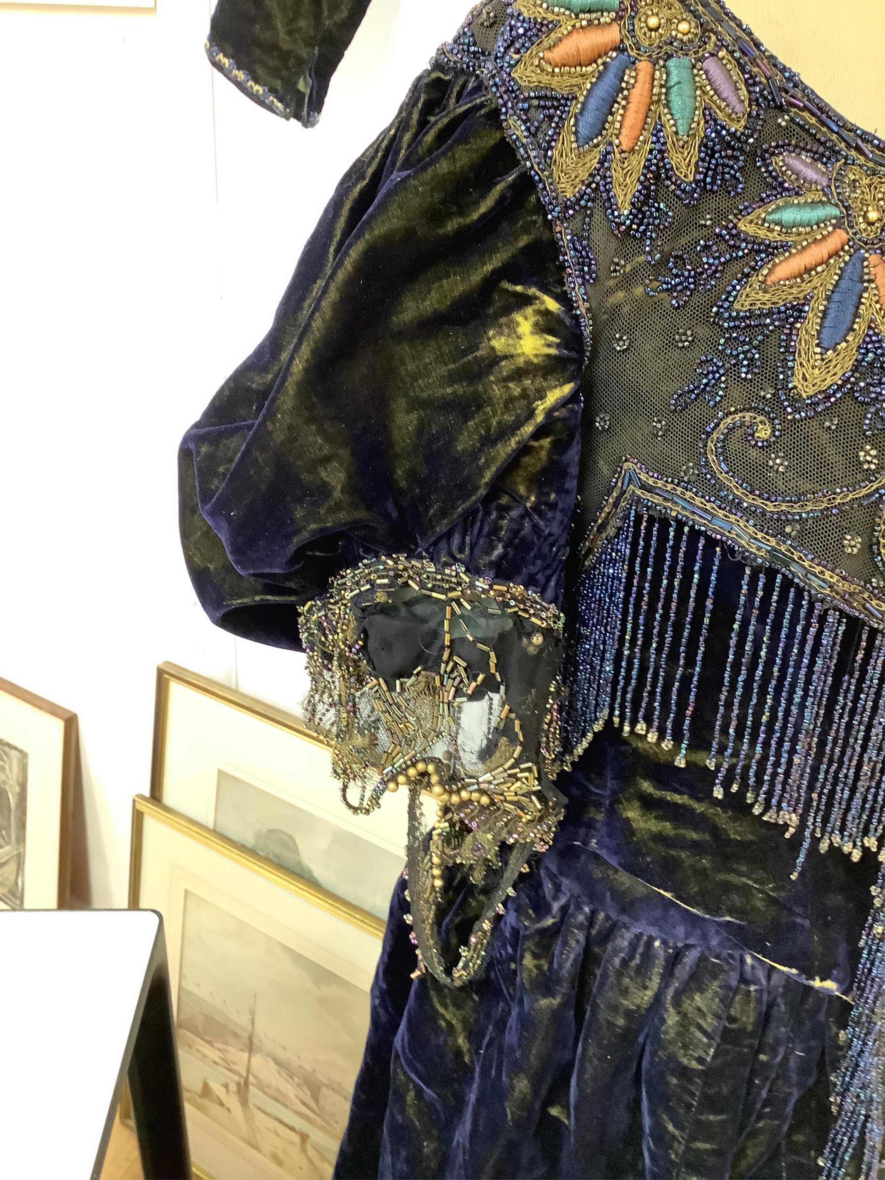 A 19th century ladies silk velvet matching long sleeved jacket/bodice, and skirt, together with another matching short sleeved bead worked bodice and white feather headdress.(4). Cape 106cm long. Condition - Both bodices